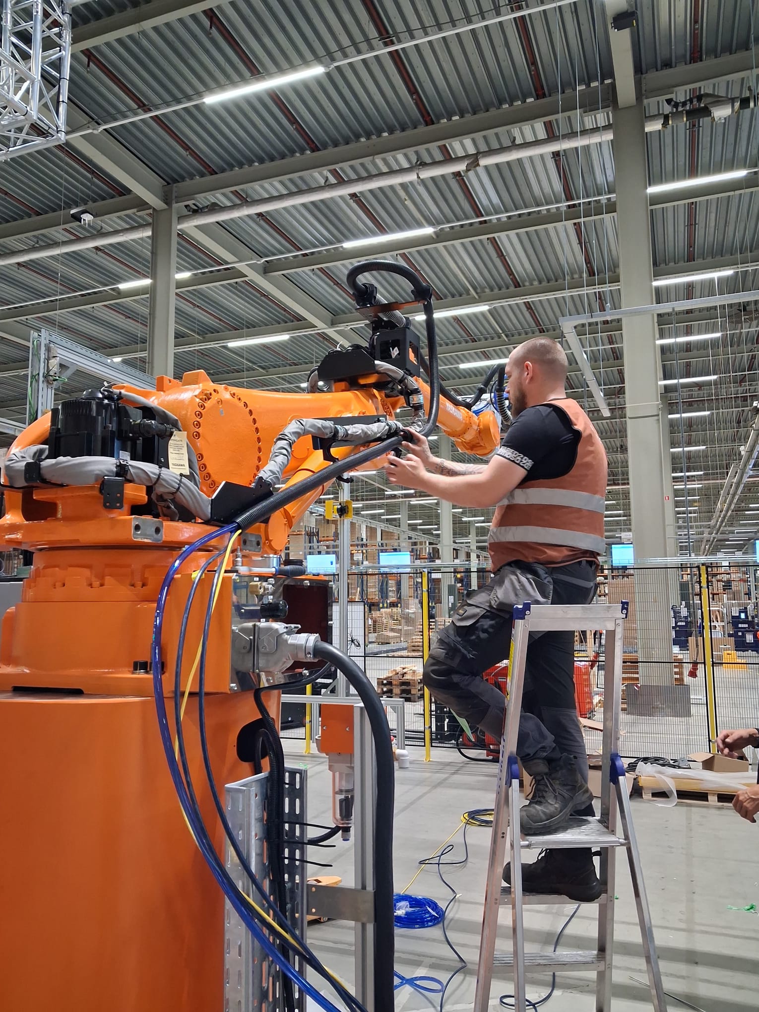 Wisman monteur vervangt Reiku beschermslangen op een Yaskawa robotarm bij Mujin Europe