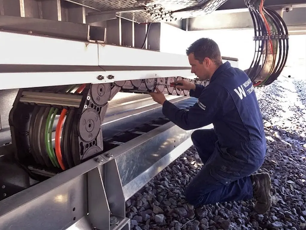 Monteur die een kabelrups installeert op een industriële machine