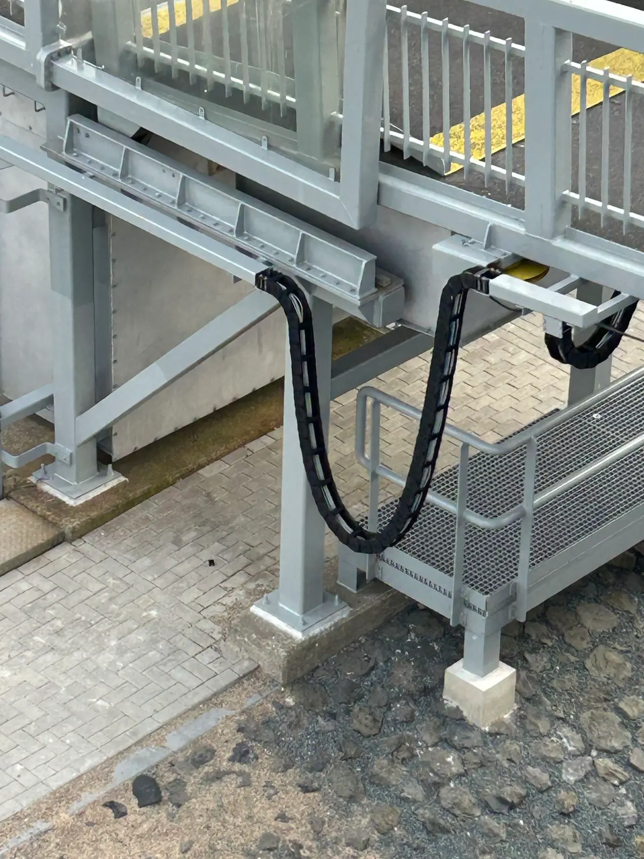 Tsubaki Kabelschlepp kabelrups gemonteerd op een metalen loopbrug in een havenomgeving